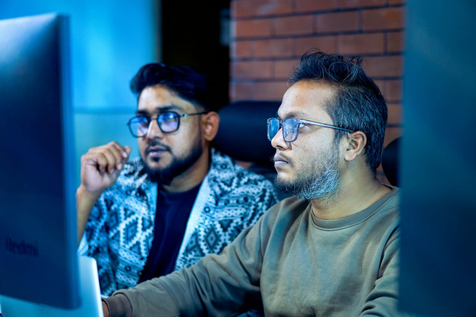Two engineers looking closely at the same computer screen