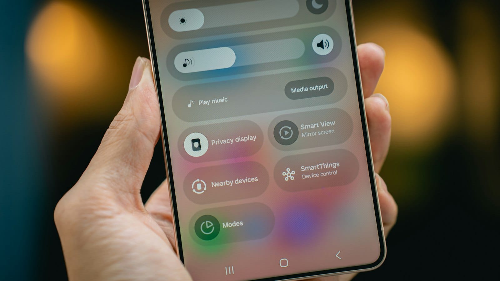 A hand holding a Samsung phone showing the Android quick settings panel