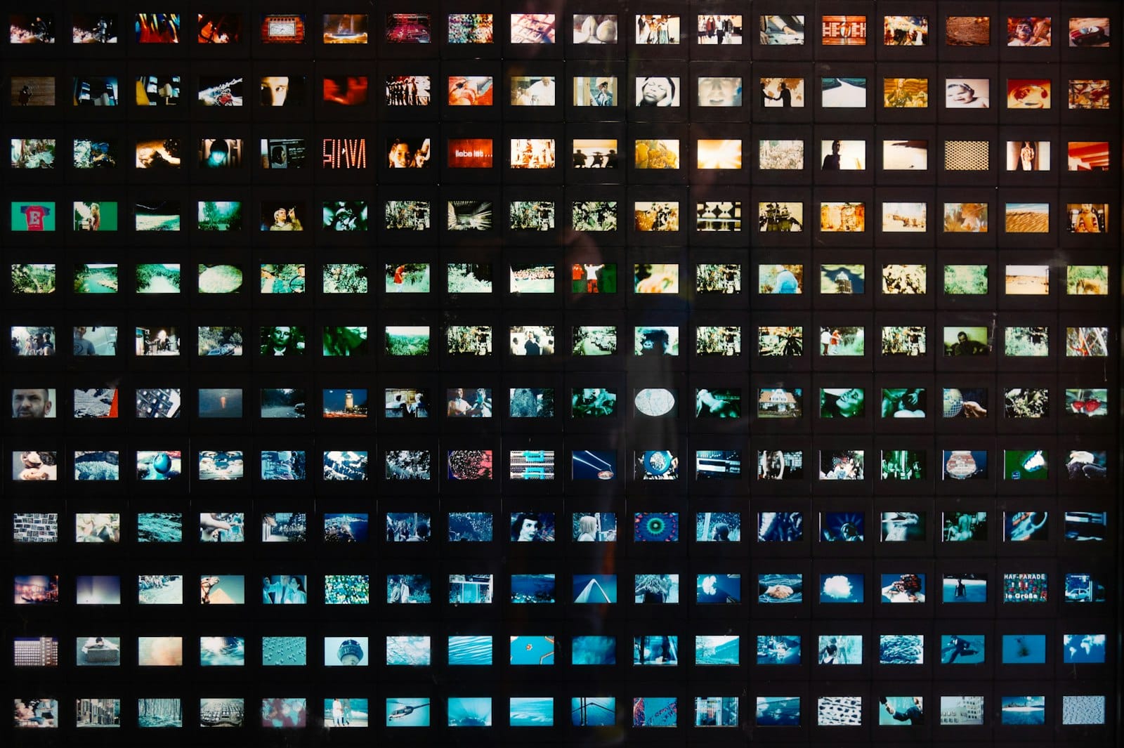 A dense grid of small images arranged on a dark wall