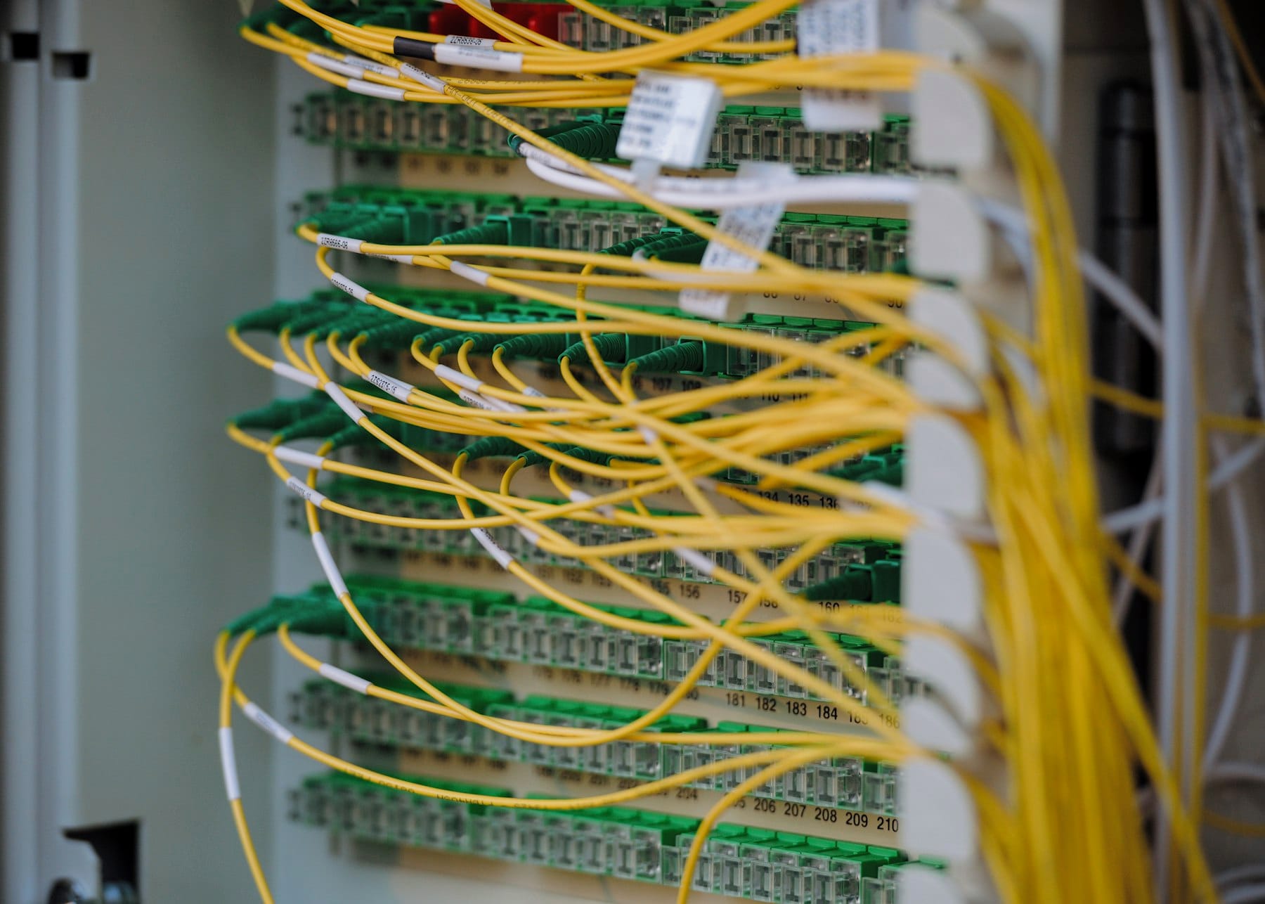 Yellow and green fibre optic cables neatly connected in a network cabinet