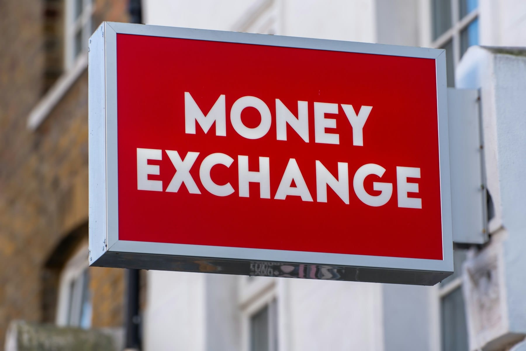 A red street sign with white lettering reading money exchange