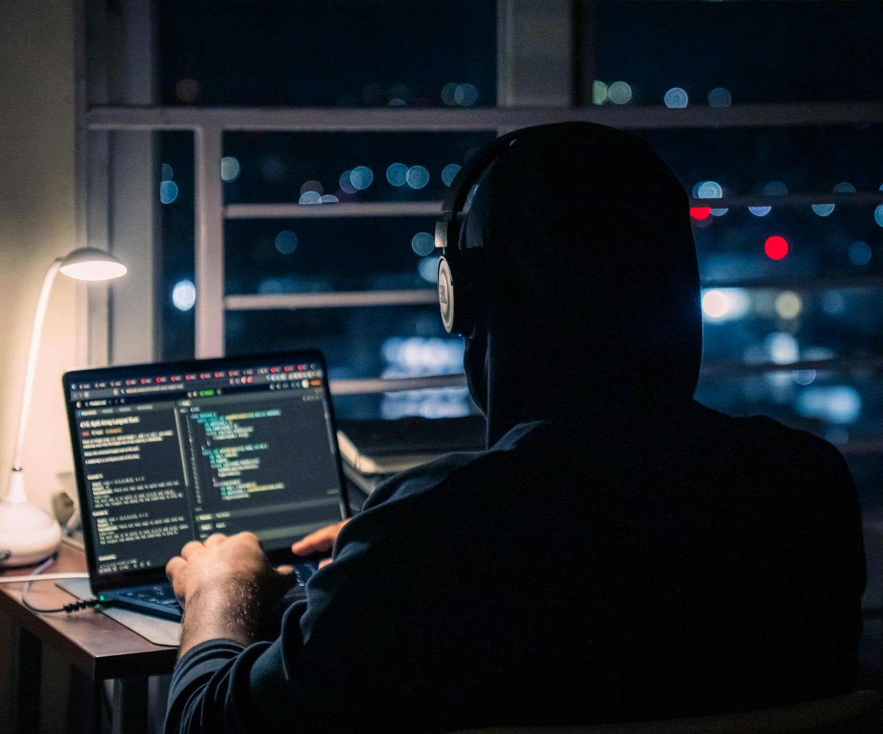 A person working alone on a laptop at night