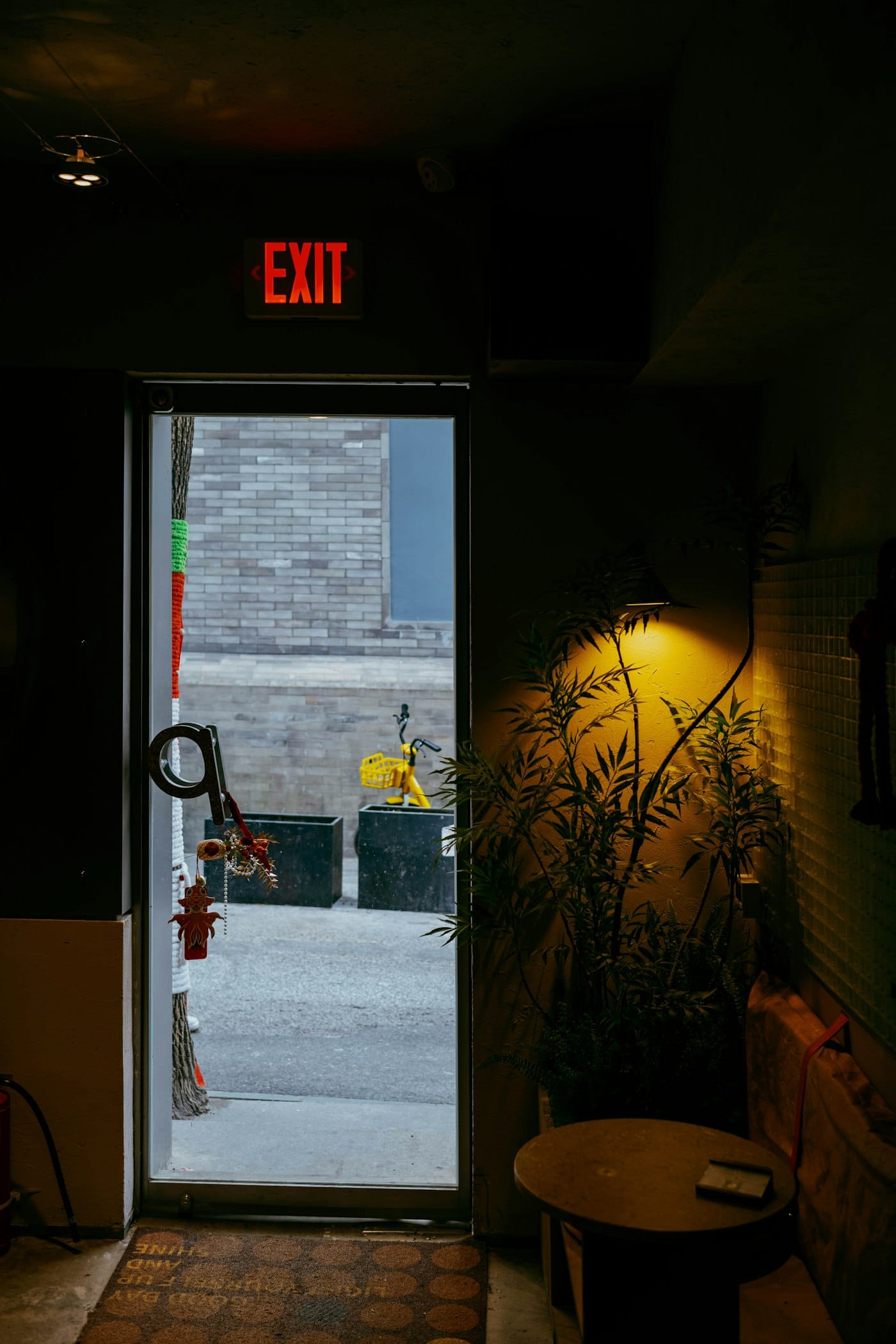 An illuminated exit sign above an open doorway leading outside