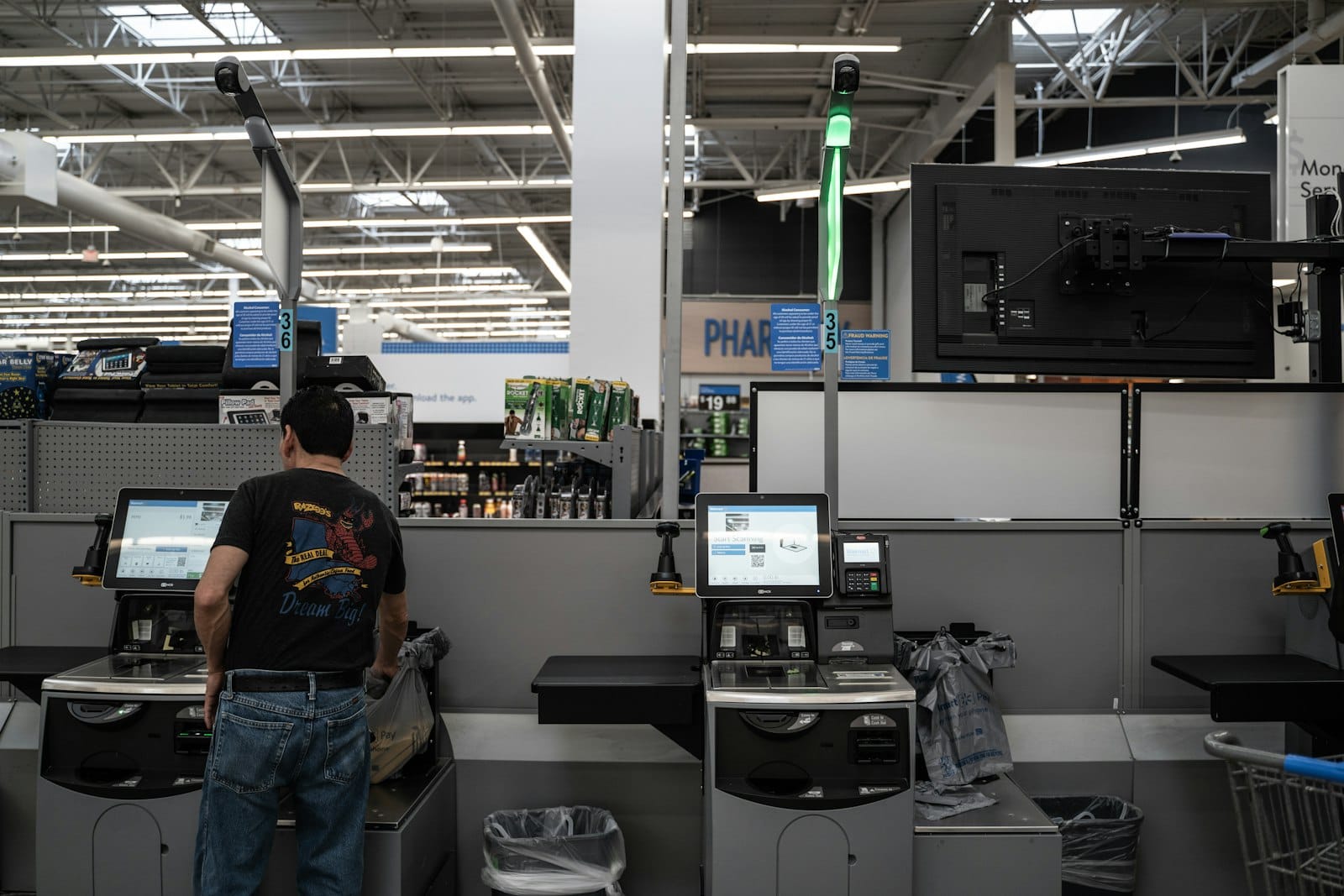 A shopper at a row of self-checkout tills in a supermarket