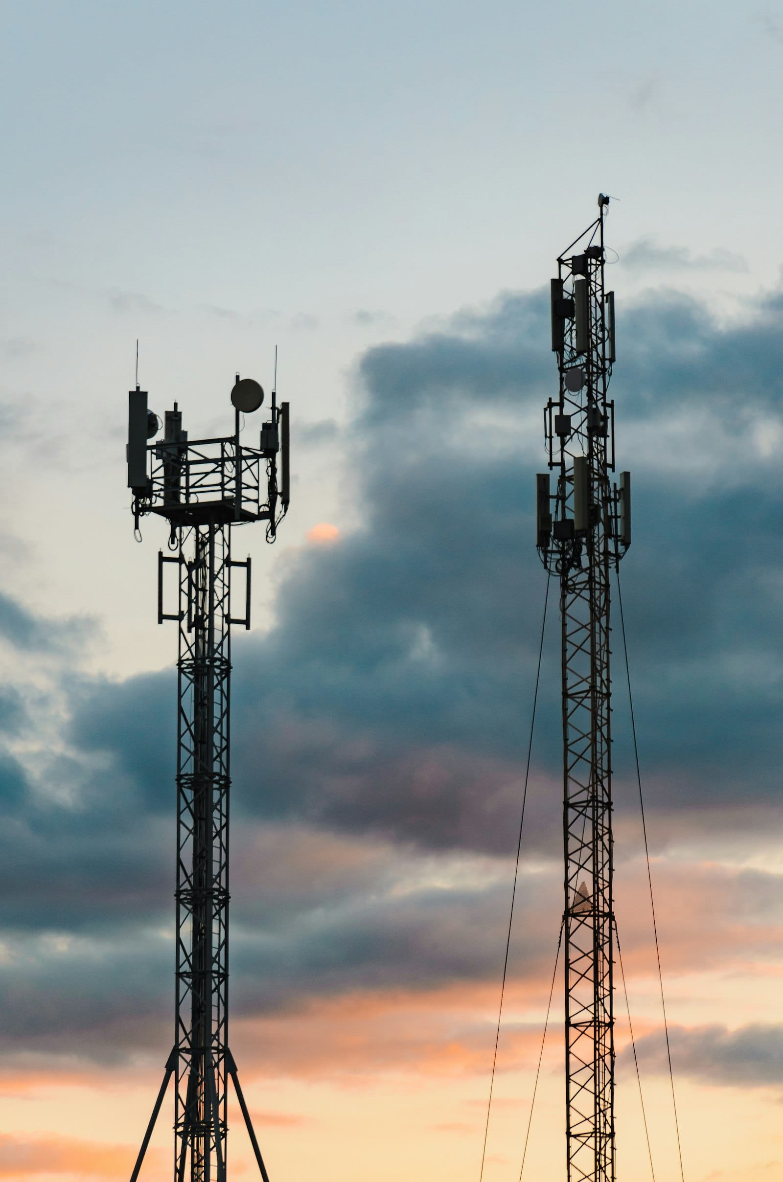 Two mobile phone towers against a cloudy sky