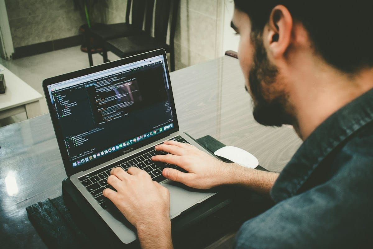 A man working on code on a laptop at a desk