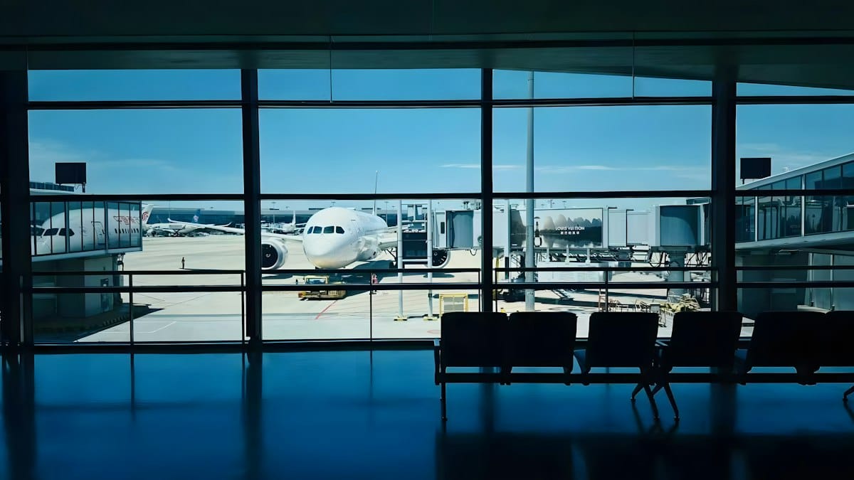 An airliner parked at a gate, seen through the windows of an empty departure lounge