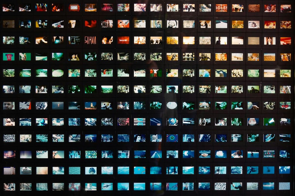 A dense grid of small images arranged on a dark wall
