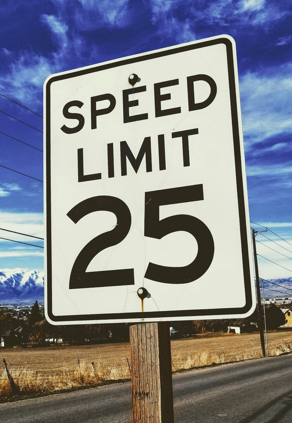 A speed limit 25 sign by a road in winter