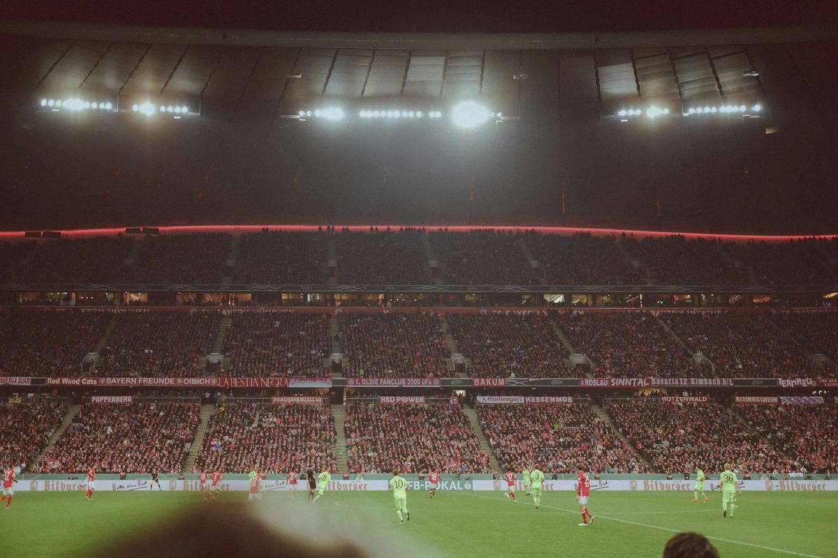 A footballer standing alone on the pitch in a stadium on matchday