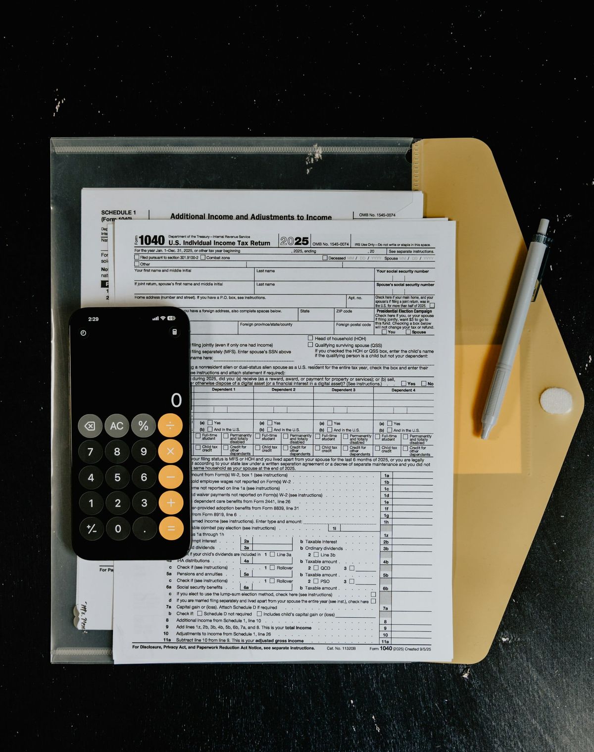 Tax forms with a calculator and a pen on a desk