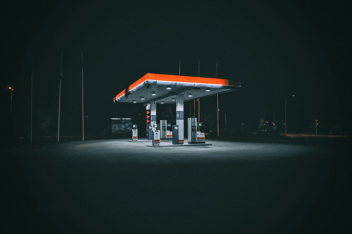 An empty petrol station lit up at night with no cars or people at the pumps