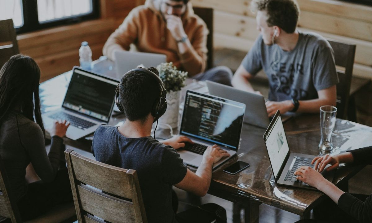 A group of colleagues working on laptops around a shared table