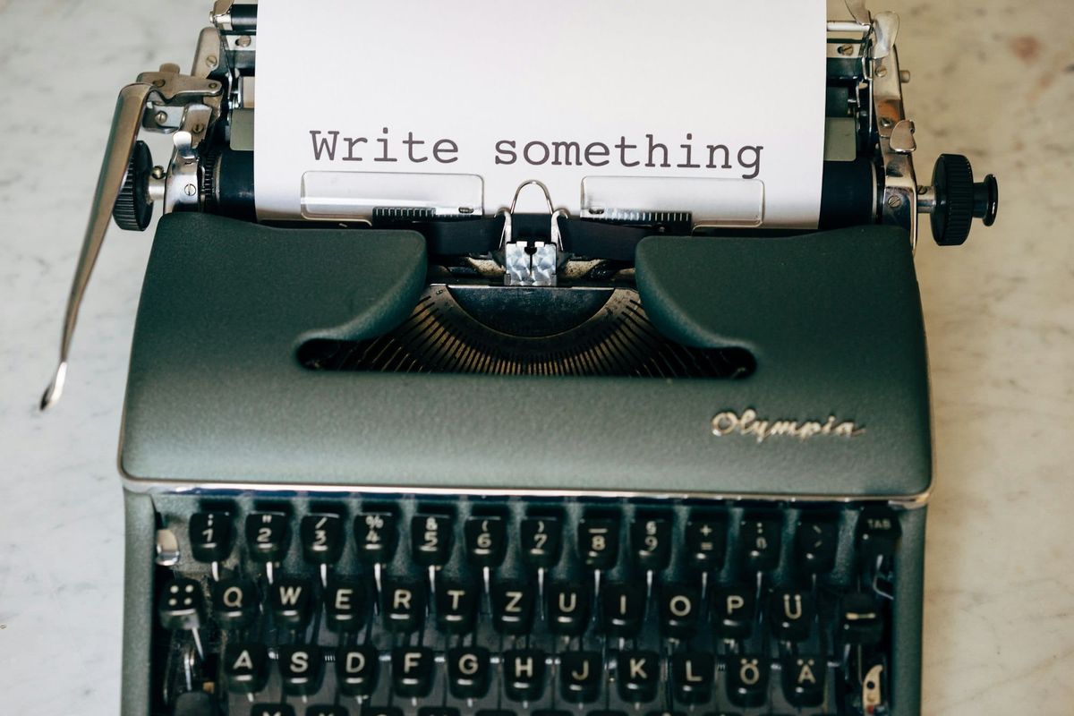An Olympia typewriter on a marble surface with a sheet of paper reading Write something