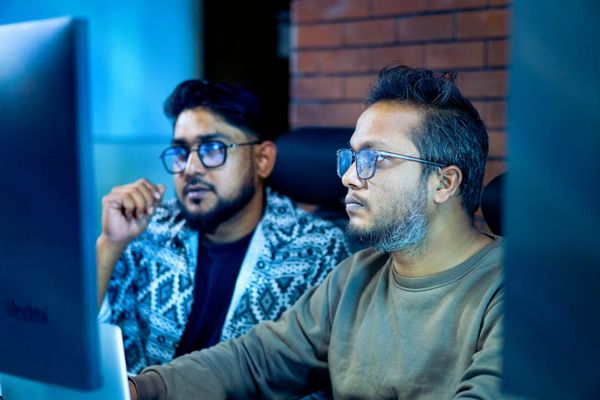 Two engineers looking closely at the same computer screen
