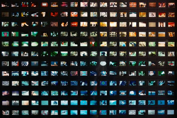 A dense grid of small images arranged on a dark wall
