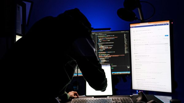 A person working at a dual-monitor workstation in a darkened room