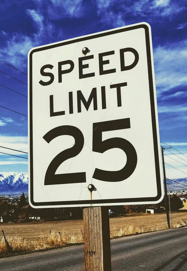 A speed limit 25 sign by a road in winter