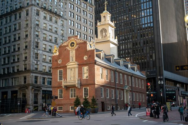 Boston's Old State House, a red brick building with a white clock tower, surrounded by modern office towers