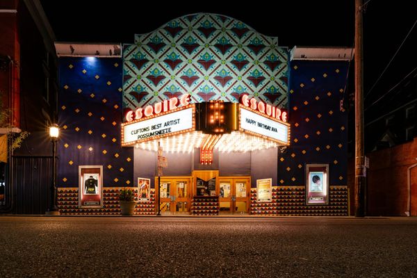 The Esquire Theatre in Cincinnati at night, its marquee lit in red and white above the entrance