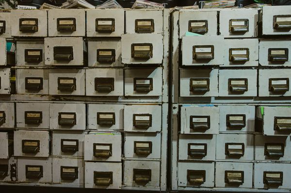 Rows of old metal filing cabinets with paper labels on every drawer