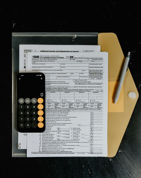 Tax forms with a calculator and a pen on a desk