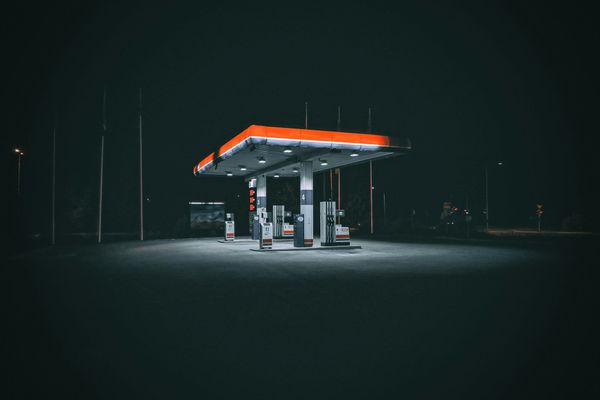 An empty petrol station lit up at night with no cars or people at the pumps