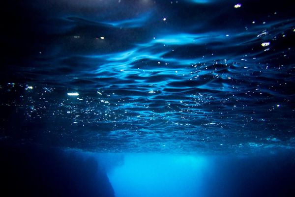 Sunlight filtering down through blue water into darkness below