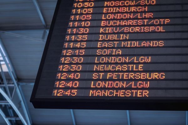 A departure board at an airport seen from below
