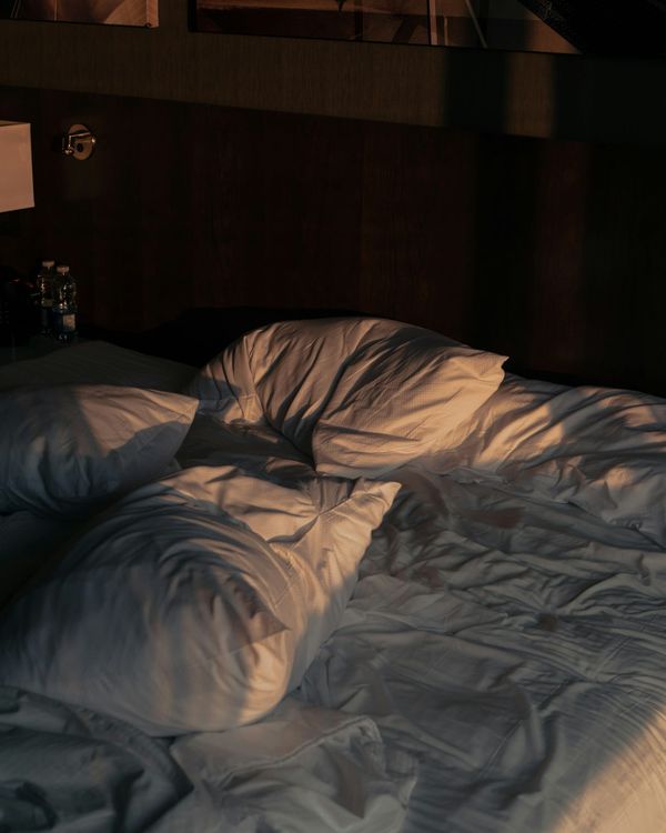 An unmade bed with white sheets and pillows
