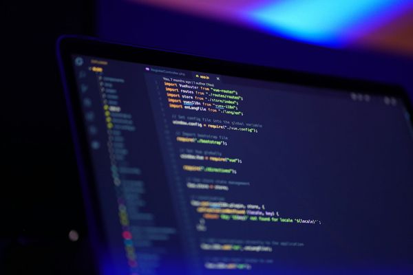 A laptop screen showing colourful lines of program code in a code editor