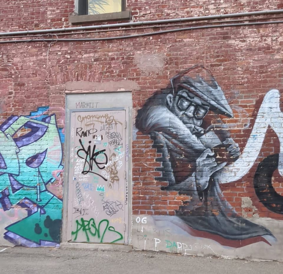 photo: graffiti on a doo and brick wall, painting of a jazzy looking guy 