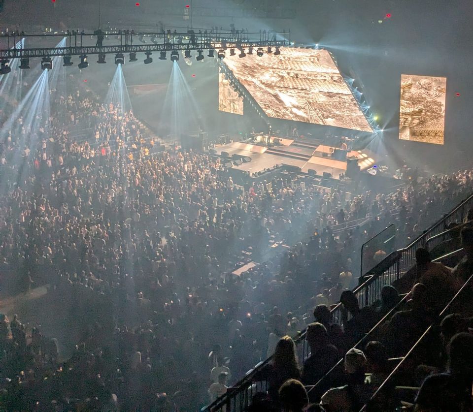 photo: crowded arena, stage, large monitors with swimmy gold-hued graphics of pagodas & such