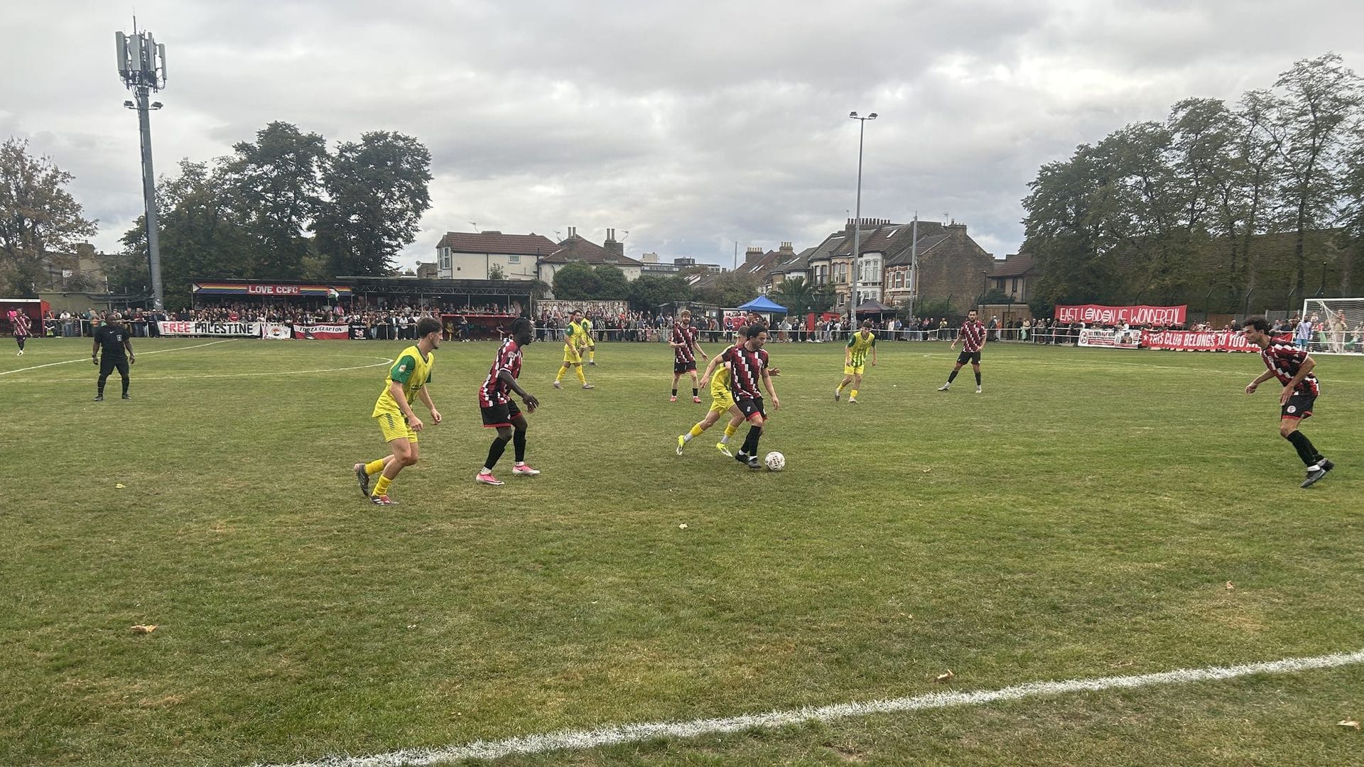 Clapton CFC and Great Wakering Rovers in midfield at the Old Spotted Dog, terraced houses and a packed far side behind
