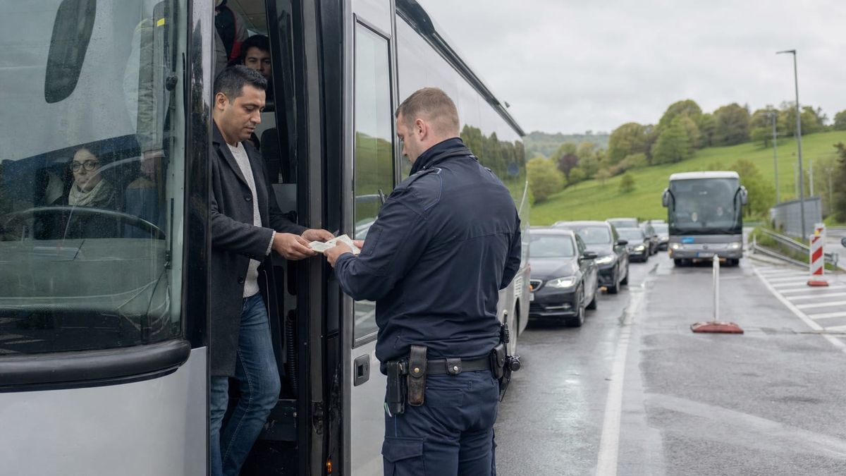 Policial verifica documentos de um passageiro em um ônibus na fronteira terrestre da Alemanha
