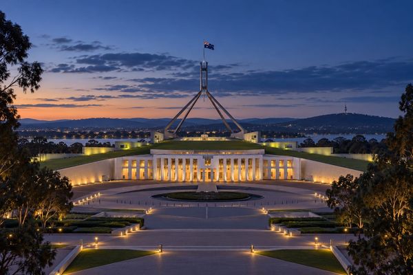 Representação ilustrativa do Parlamento australiano em Canberra ao anoitecer, com fachada iluminada e jardins no primeiro plano.