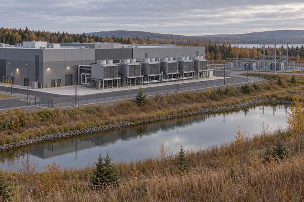 Edifício industrial de um centro de dados com equipamentos de resfriamento, infraestrutura elétrica e vegetação, em paisagem ilustrativa de outono.