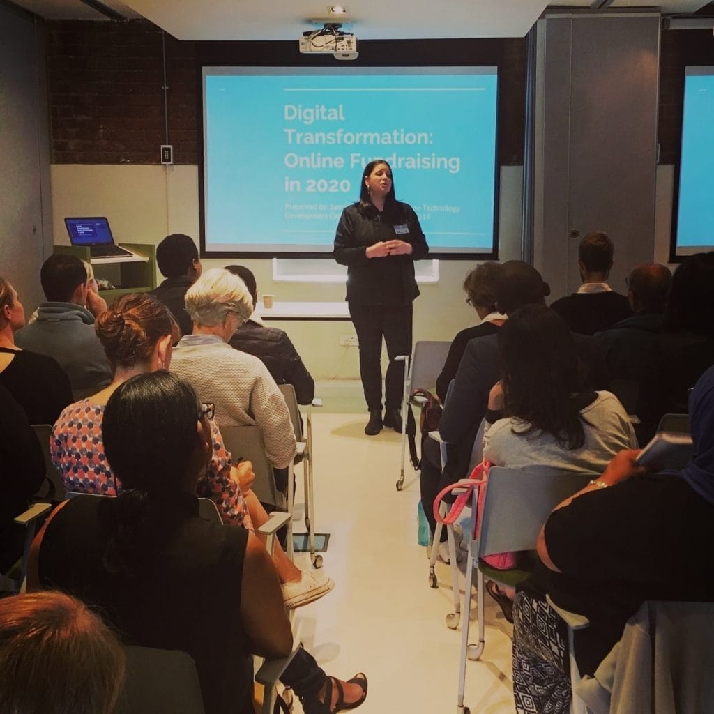 Samantha Barnard presenting a session on digital transformation and online fundraising at the ThinkGood Summit 2020, standing in front of a full room of nonprofit professionals.