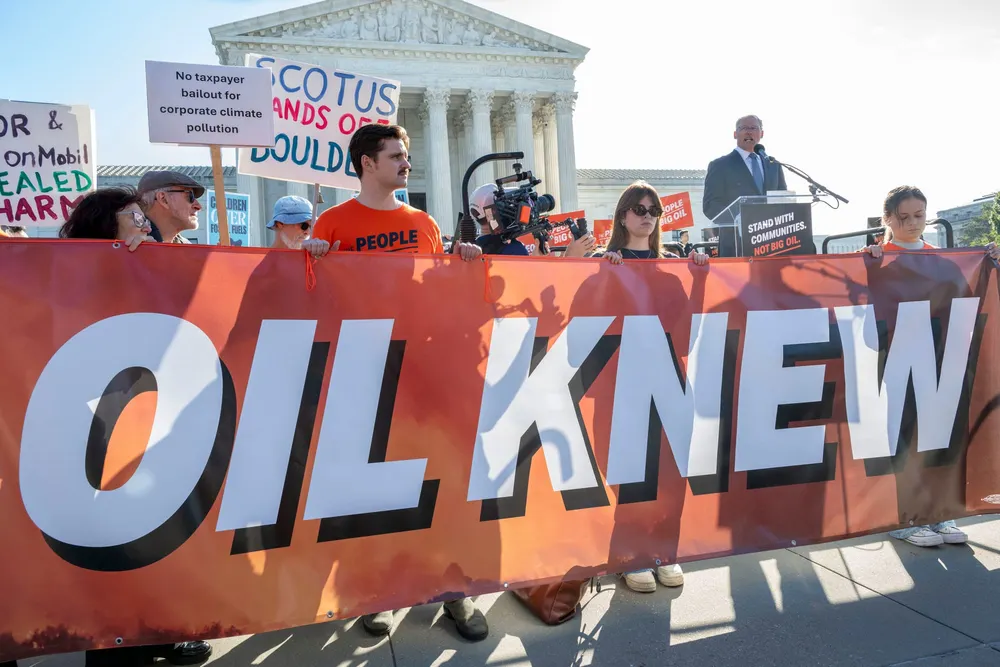 Rally outside the SUpreme Court on Monday, holding sign "oil knew"