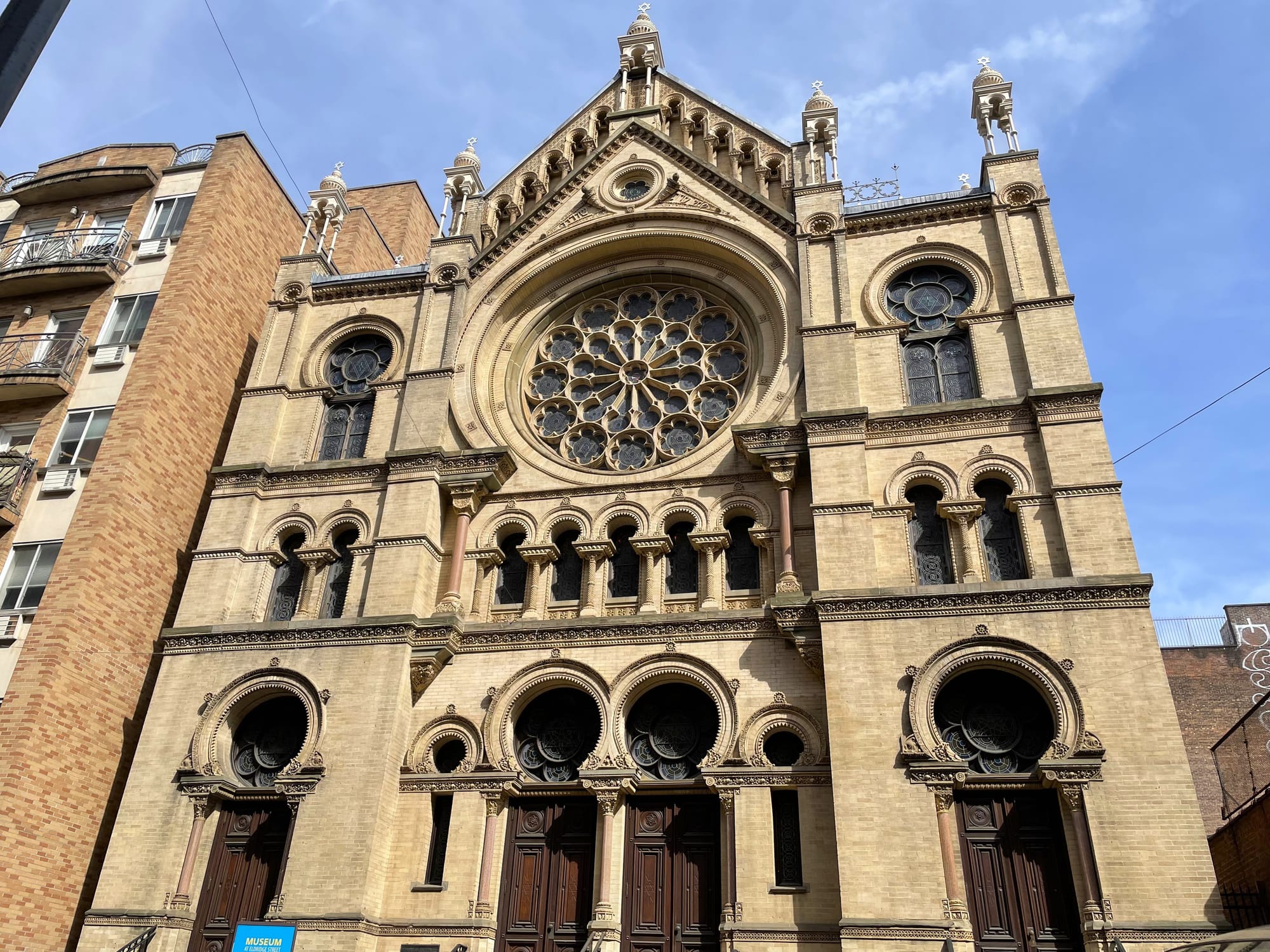 Exterior of a historic synagogue building with brick exterior and a rose stained glass window