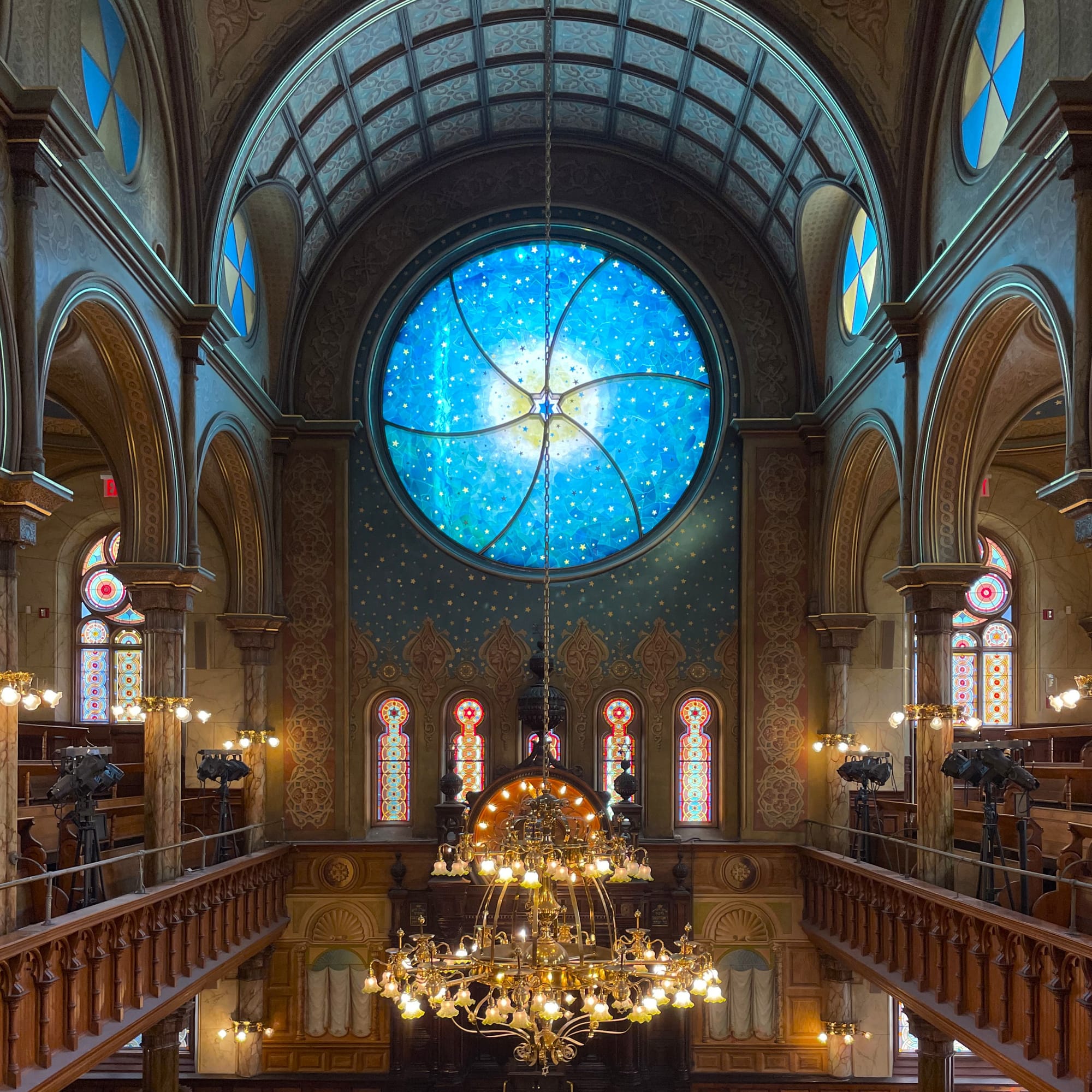 Interior of a historic synagogue with a vivid blue stained glass window in the center