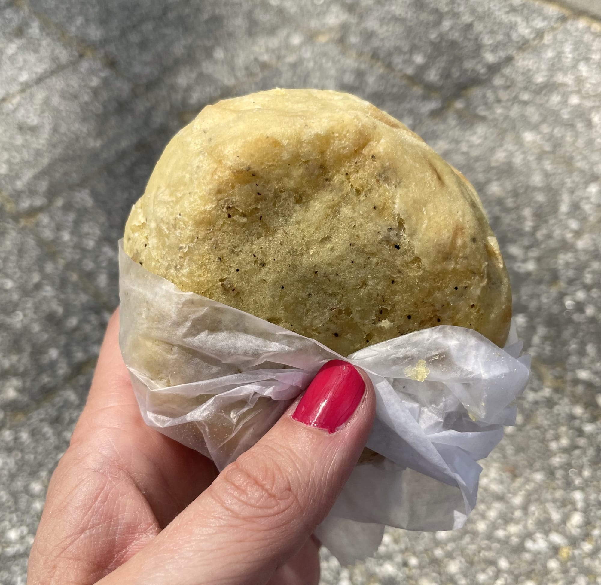 Stacy's hand holding a round pastry stuffed with mashed potatoes