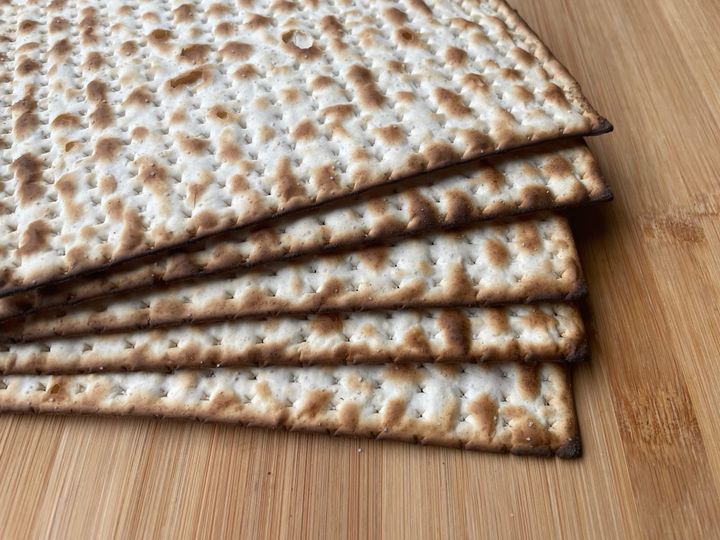 Five pieces of matzah on a wooden cutting board