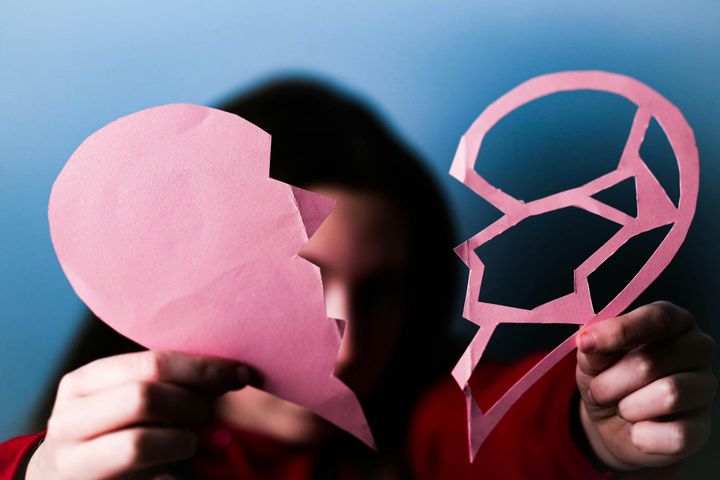 Child holding a paper heart that has been torn in half