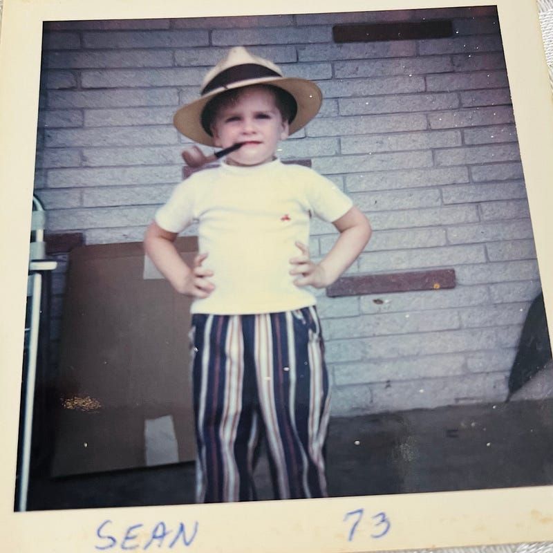 A picture of myself at four-years-old in 1973 — wearing my grandfathers hat, with his corncob pipe in my mouth.