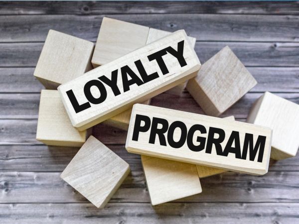 Two wooden blocks labeled "LOYALTY" and "PROGRAM" are placed atop a scattering of smaller wooden cubes on a wooden background.