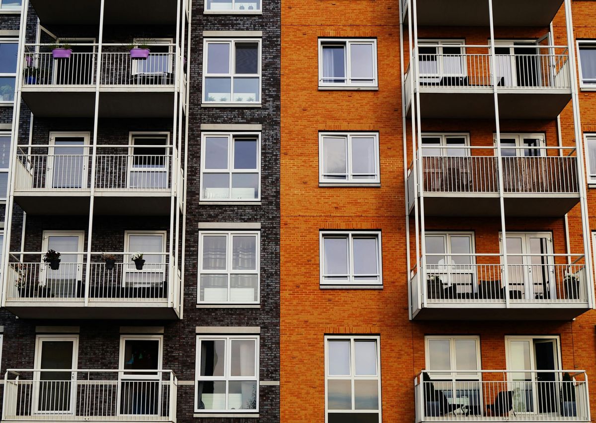 Apartment exterior showing windows and balconies. Photo by George Becker: https://www.pexels.com/photo/photography-of-orange-and-gray-building-129494/