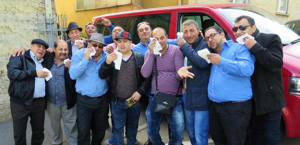 Twelve bandmates jokingly crying in front of van