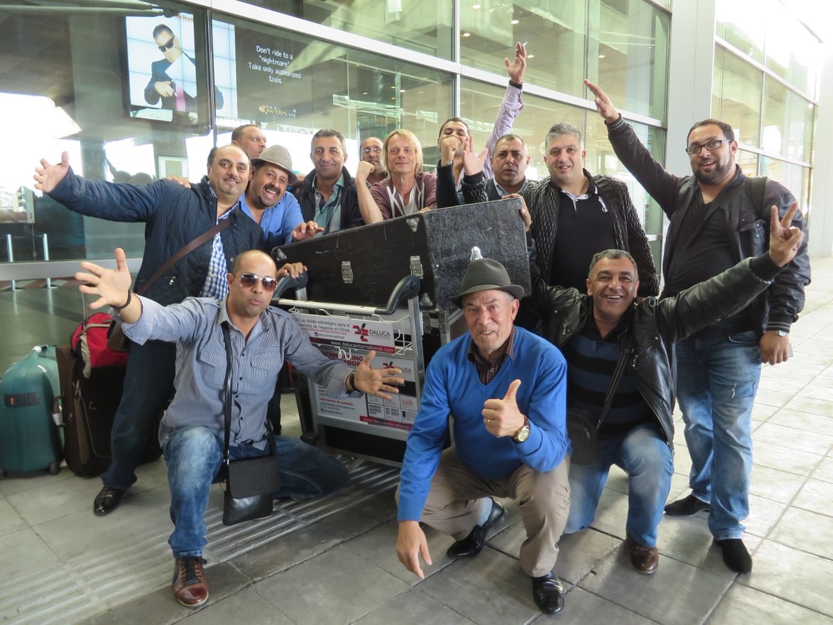 Twelve bandmates plus manager Henry Ernst waving outside of airport