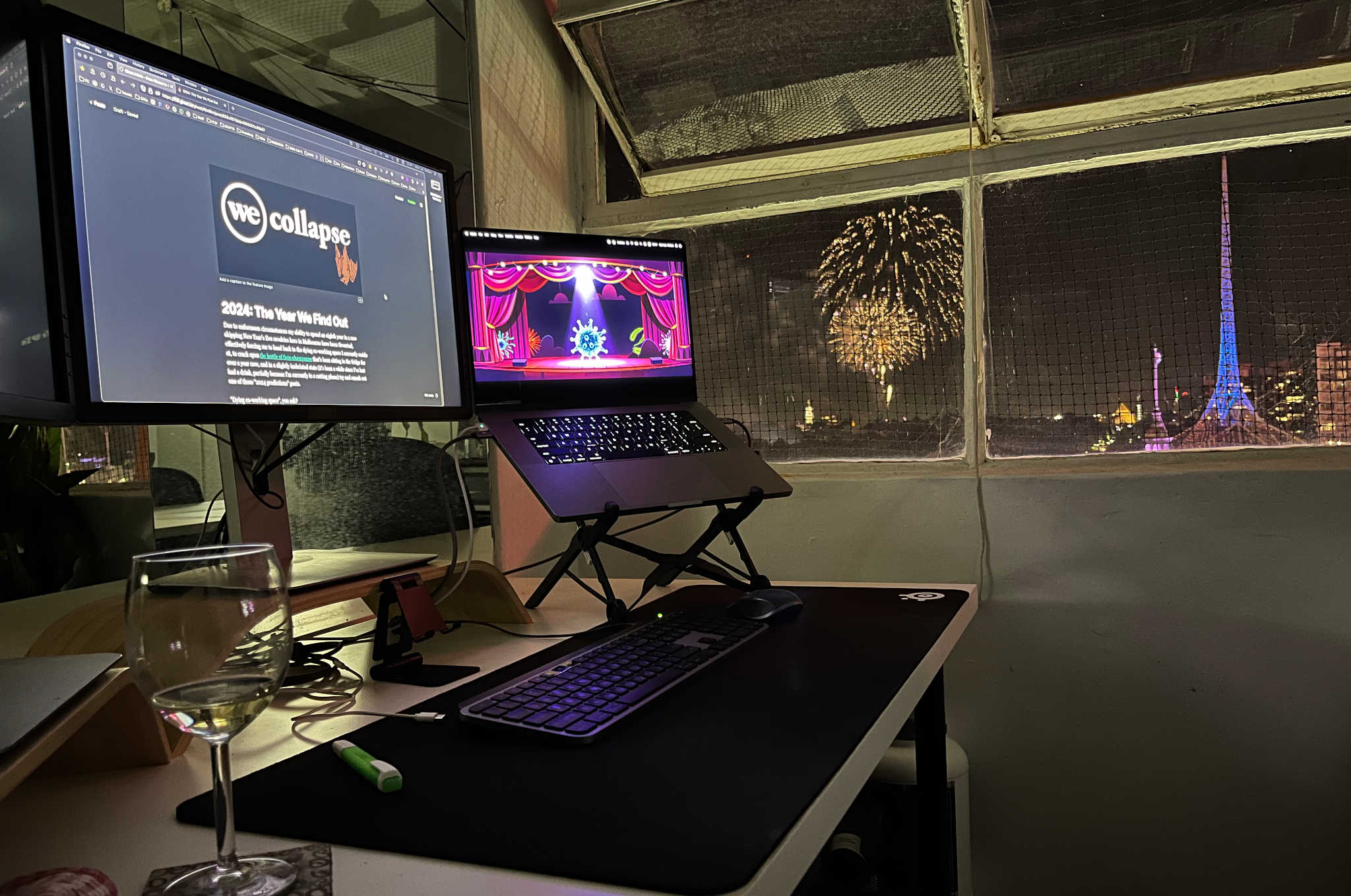 My workstation in the co-working space I'm currently at with the draft of this post on the two computer screens, Melbourne's NYE fireworks seen through the (cracked open) window